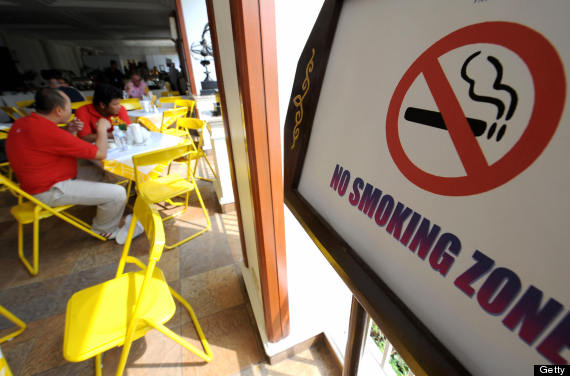 Thai men sit next to a no-smoking sign d