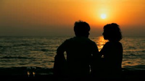 stock-footage-silhouette-of-young-man-and-woman-sitting-on-the-beach-and-talking-to-each-other-beautiful-sunset